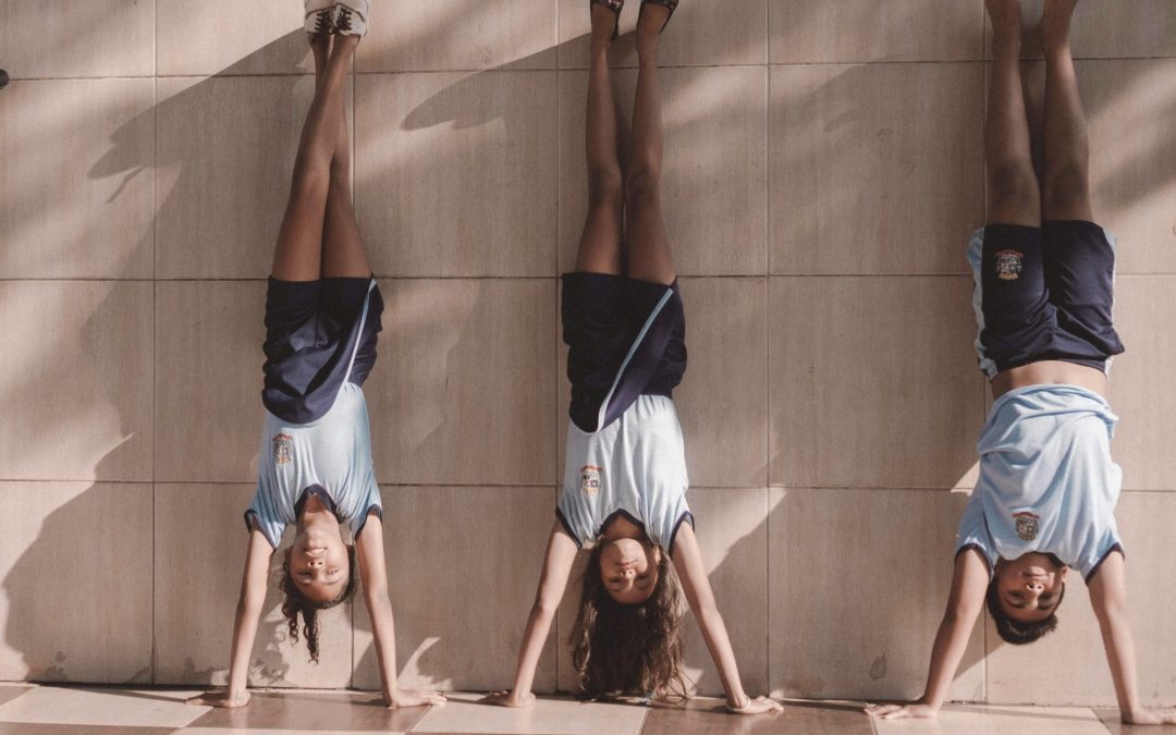 Vier junge Teenager machen Handstand an einer Wand